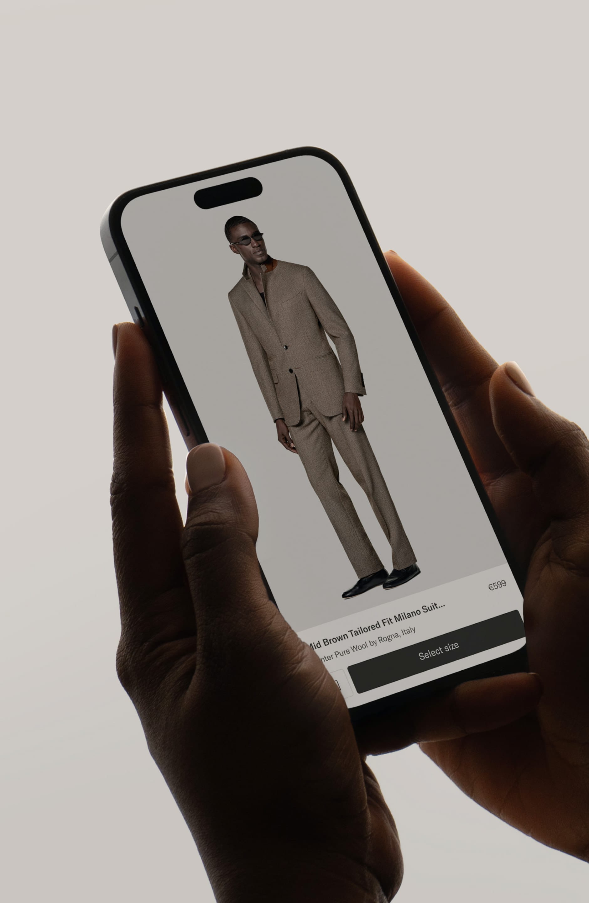 A person holds a smartphone displaying a fashion app with an image of a man in a beige suit against a white background.