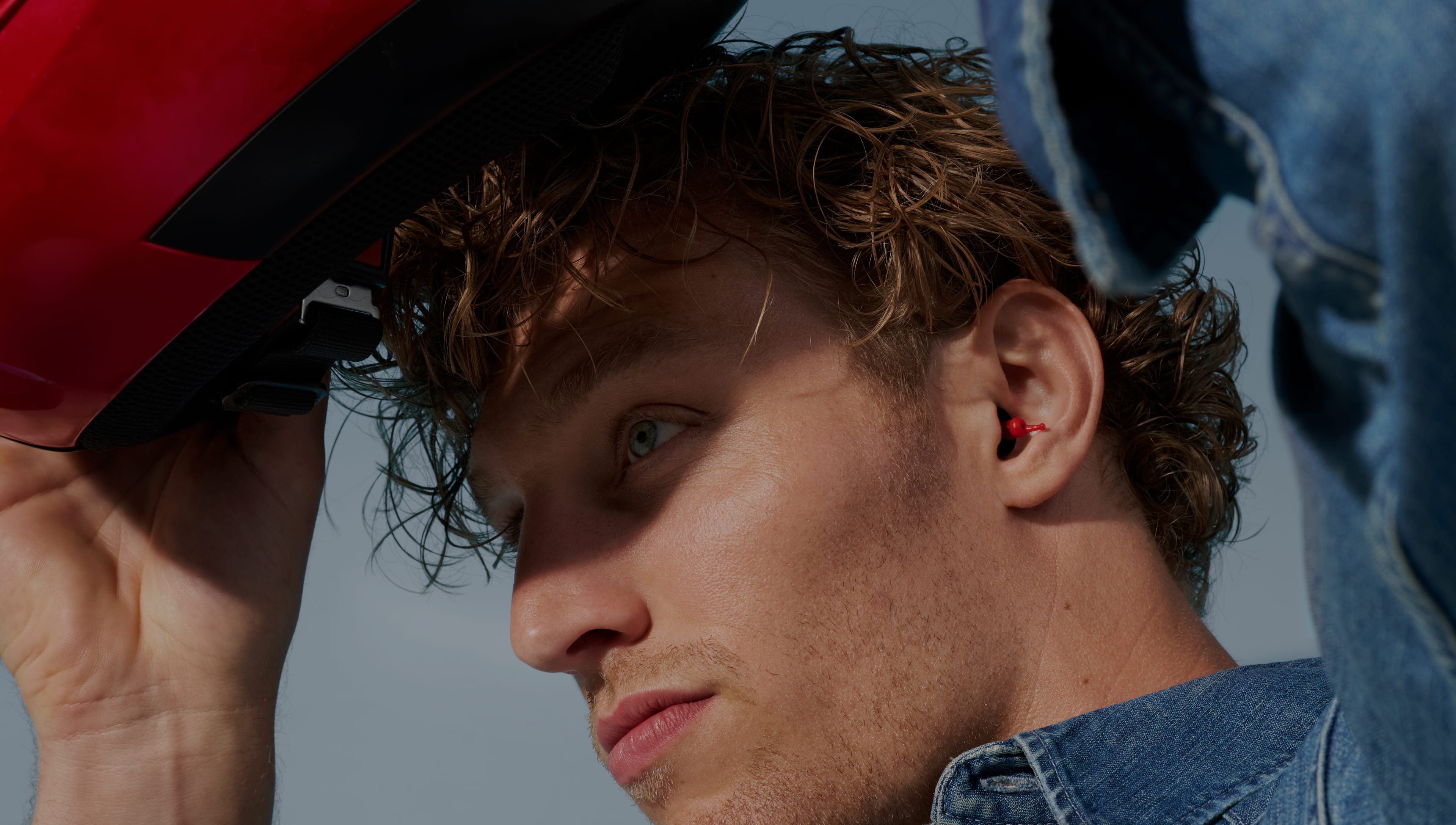 Man putting on his motor helmet while wearing Alpine earplugs