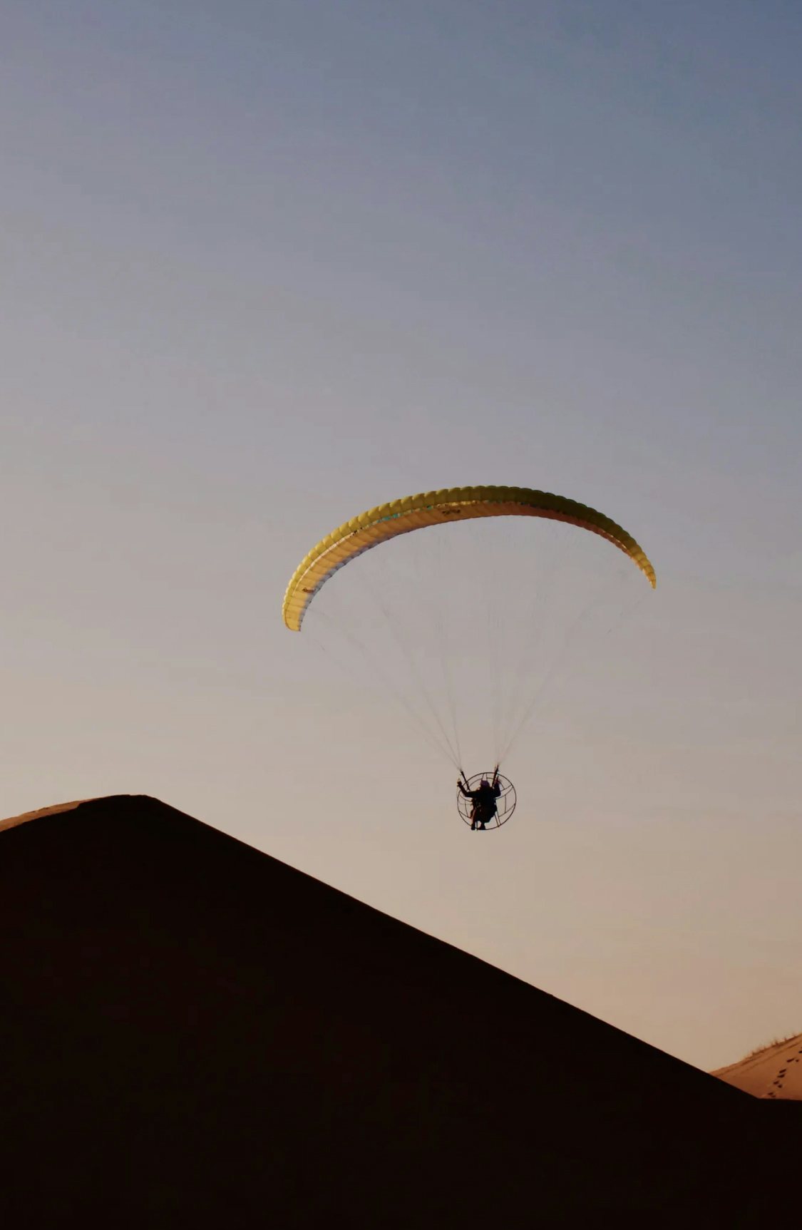 man paragliding in the desert