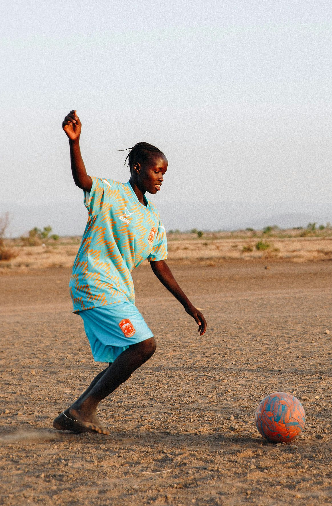 Girl kicking a football wearing vibrant sportswear in Kenya