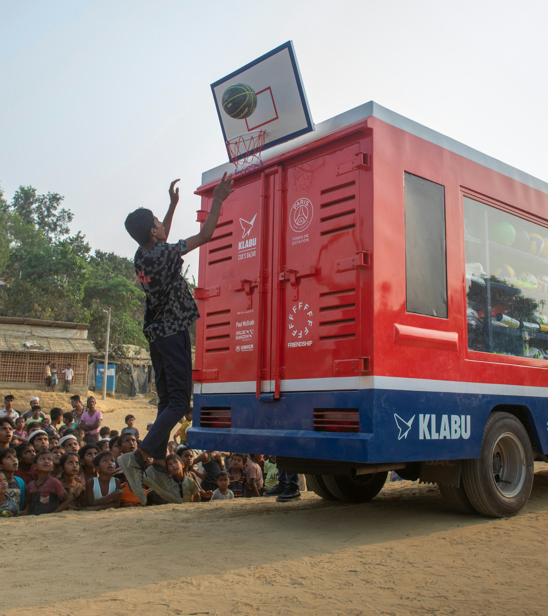 Child in Bangladesh playing basketball by a mobile sports library